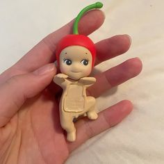 a hand holding a small plastic toy with a red hat on it's head