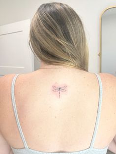 a woman with a dragonfly tattoo on her back