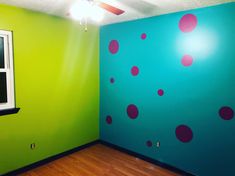 an empty room with green walls and pink polka dots painted on the wall next to a window