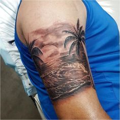 a man's arm with a palm tree and ocean scene tattoo on his left shoulder