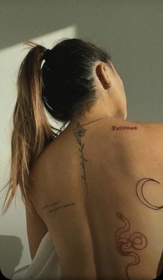 a woman with her back turned to the camera, has tattoos on her upper half