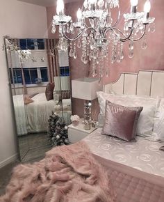 a bedroom with a bed, chandelier and mirror in the middle of it