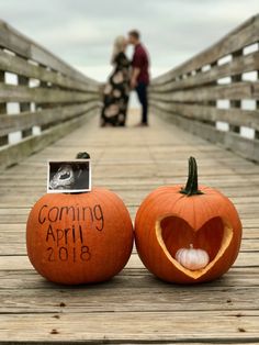 two carved pumpkins sitting on top of a wooden bridge with the words coming april in front of them