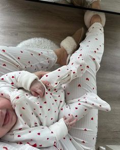 a baby laying on top of a wooden floor next to a stuffed animal and wearing pajamas