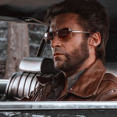 a man with sunglasses sitting in the back seat of a car looking off into the distance