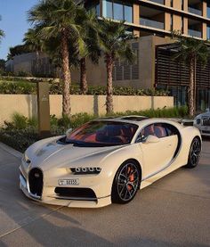 a white bugatti parked in front of a building next to a silver car