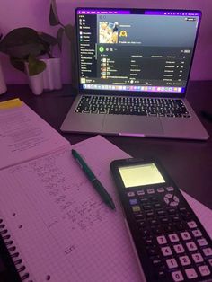 a laptop computer sitting on top of a desk next to a calculator and notebook