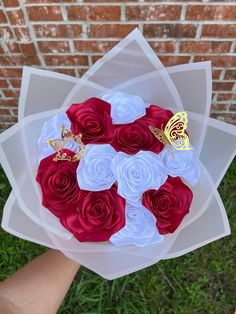 a bouquet of red and white roses with butterflies on them in front of a brick wall