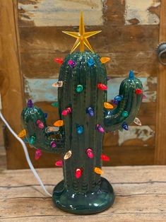 a green cactus with colorful lights and a star on it's top sitting on a wooden table