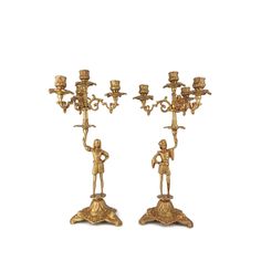 two golden candelabra with figurines and candlesticks