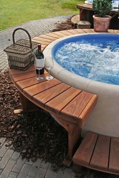 a hot tub sitting on top of a wooden bench next to a bottle of wine