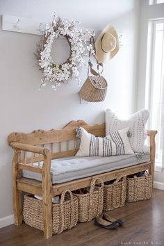 a wooden bench with baskets on it and a hat hanging from the wall next to it