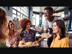 group of friends having lunch together at a restaurant, smiling and looking at each other