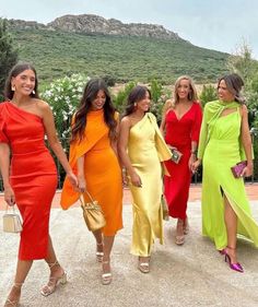 four women in different colored dresses walking together