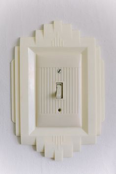 a white wall mounted light switch plate with an art deco style design on it's side