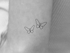 two small butterfly tattoos on the ankle, one with black ink and one with white ink