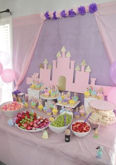 a table topped with lots of food and desserts next to a princess's castle