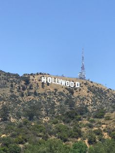 the hollywood sign on top of a hill with trees around it and a radio tower in the background