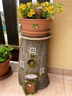 a potted plant on top of a tree stump with flowers growing out of it