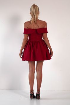 a woman in a short red dress is looking back at the camera with her hands on her hips