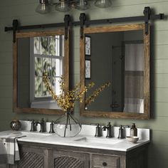 a bathroom vanity with two mirrors above it and a vase on the counter in front of it