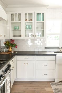 a kitchen with white cabinets and black counter tops