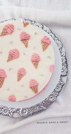 a cake decorated with pink icing and ice cream cones on a silver platter