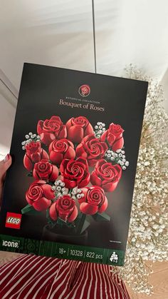 a person holding up a box with roses on it