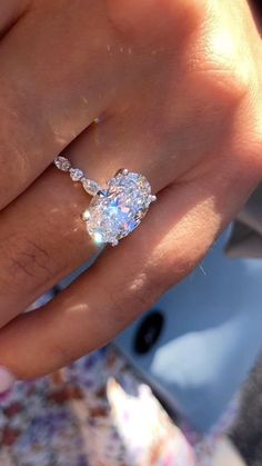 a woman's hand with a diamond ring on top of her finger and an engagement band