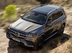 a grey mercedes suv driving down a dirt road