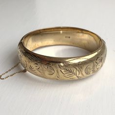 A Vintage bangle displaying beautiful leaf engravings. The wonderful warm yellow gold colour really shows off the detailing perfectly. CONDITION: Wear consistent with age and use. Please see photos for more detail. Strong clasp.  HALLMARKED SILVER, ASSAYED IN BIRMINGHAM 1970 BAND WIDTH: 18mm APPROX. INTERNAL MEASUREMENT (AROUND): 175mm APPROX. DIAMETER (INTERNAL): 55mm x 60mm WEIGHT: 24.4 grams ) Luxury Vintage Engraved Bangle, Classic Gold Etched Bangle, Gold Etched Cuff Bracelet For Wedding, Antique Etched Gold Bracelets, Antique Etched Gold Bangle Bracelet, Antique Etched Gold Bracelet, Vintage Gold Bangle With Intricate Design, Gold Etched Bracelet Jewelry, Ornate Gold Etched Bangle