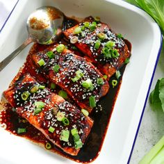 salmon with sesame seeds and green onions in a white casserole dish next to lettuce