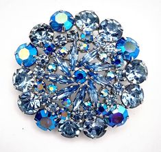 The brilliance of these stones is mind-blowing as is the steep contrast between the baby blue and the dark sapphire blue aurora borealis rhinestones. All are prong set in silver tone metal. This EXQUISITE brooch is in excellent vintage condition and measures 1 7/8 inches. Blue Crystal Brooches For Gifts, Blue Round Brooch For Gift, Blue Round Brooches For Gifts, Round Blue Brooches For Gifts, Blue Crystal Brooches With Rhinestones, Blue Aurora, Blue Aurora Borealis, Dark Sapphire, Rhinestone Brooches