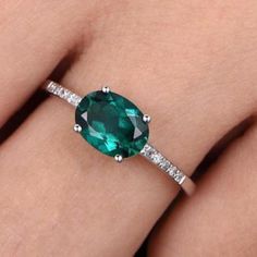 a woman's hand with an emerald and diamond ring