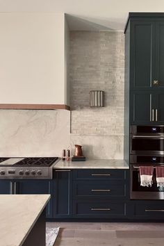 a kitchen with blue cabinets and marble counter tops, along with an oven in the center