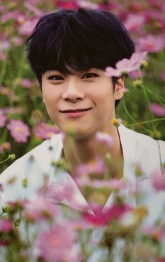 a young man standing in a field of flowers