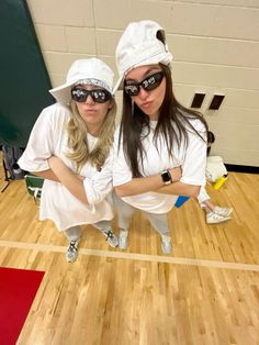 two women dressed in white posing for a photo on a basketball court with their arms crossed