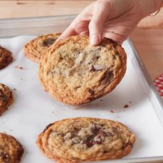 a person picking up a chocolate chip cookie