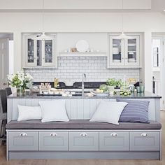 a kitchen with white cabinets and gray bench