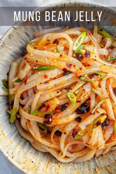 a bowl filled with noodles and vegetables on top of a white cloth covered tablecloth