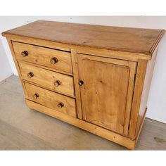 a wooden dresser sitting on top of a hard wood floor next to a white wall