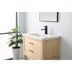 a bathroom sink with a wooden cabinet underneath it and a potted plant next to it