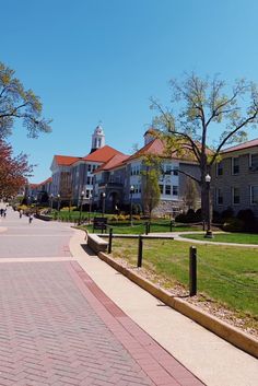 an empty street in front of some buildings with trees and grass on the side walk