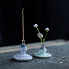 two small vases with flowers in them sitting on a table next to each other