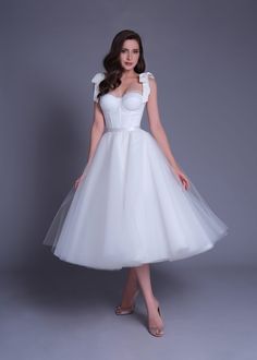 a woman in a white dress posing for the camera with her hands on her hips