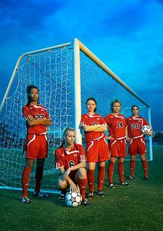 a group of young women standing next to each other in front of a soccer goal