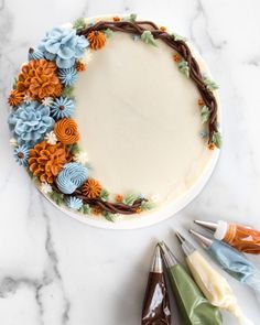 a cake decorated with flowers and crochet hooks on a marble countertop next to markers