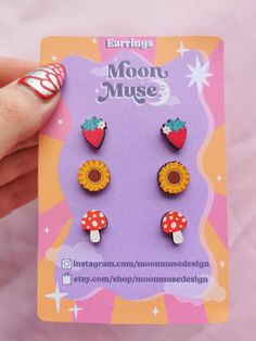 A lovely pack of 3 retro design wooden stud earrings. yellow sunflower with brown center, red mushroom with white spots and stars and red strawberry with flower.  This would make such a lovely gift! sunflower charm Measures 12mm x 12mm. mushroom charm Measures 12mm x 10mm. strawberry charm Measures 12mm x 10mm. These printed wooden charms are made from responsibly sourced, fast-growing woods on 4mm thick Maple MDF. earring posts are silver plated. Please check out my other pin badge designs and Retro Sunflower, Earrings Pack, Sunflower Charm, Strawberry Charm, Red Mushroom, 70s Boho, Red Strawberry, Badge Design, Yellow Sunflower