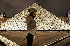 a woman standing in front of the pyramid at night with skis on her feet