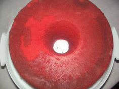 a red frosted donut sitting on top of a white cake plate with a candle in the middle